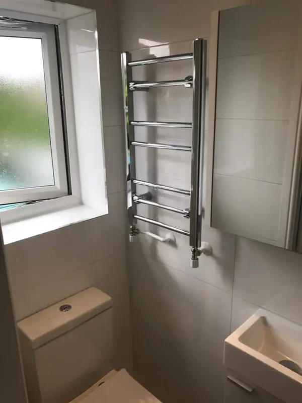Chrome ladder towel radiator under a window