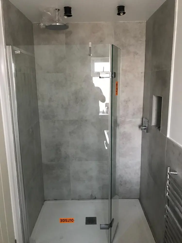 Walk-in shower with grey tiles and a glass screen