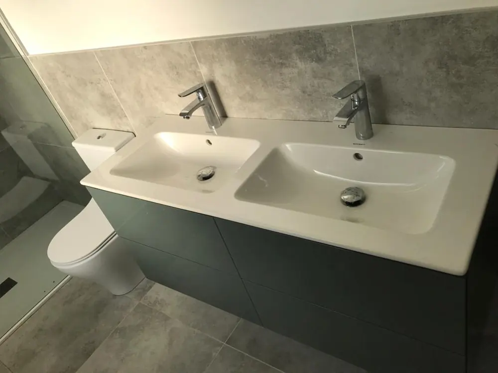 Green double vanity unit with grey stone tiles