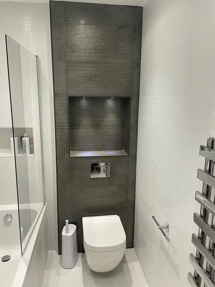 Narrow bathroom with wall hung toilet and dark feature tiles