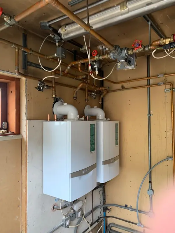 Two boilers side by side on a plant room wall