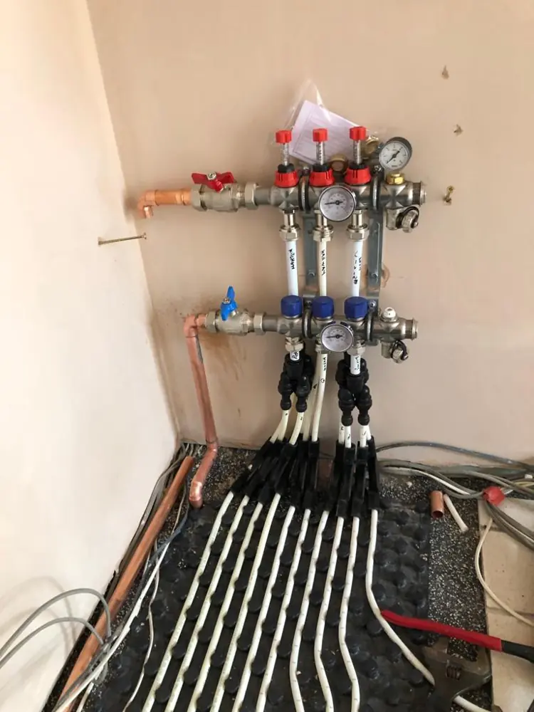 Underfloor heating manifold with flow meters and pipes to each zone